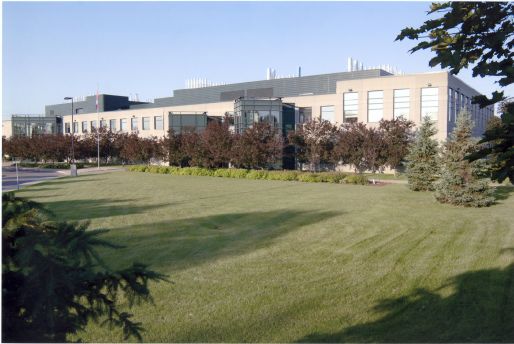 Exterior view of a large multi-storey building surrounded by grass and trees.